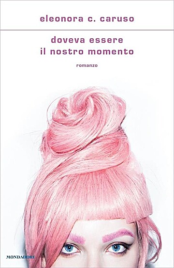 Copertina di Doveva essere il nostro momento di Eleonora C. Caruso: raffigura la testa di una ragazza, dagli occhi in su. Ha occhi azzurri e sopracciglia e lunghi capelli rosa, con un taglio asimmetrico della frangia. I capelli sono legati in una specie di crocchia sopra la testa.